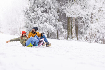 Couple sliding down the hill in the snow while on winter vacation