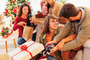 Friends exchanging and opening Christmas presents
