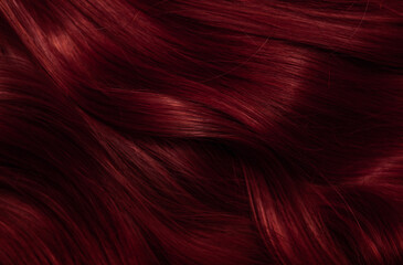 Dark red hair close-up as a background. Women's long brown hair. Beautifully styled wavy shiny...