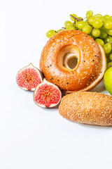 Bagel with sesame and soft fresh bun on a white background with space for text. Delicious vepechka and bread with fruit. Creative breakfast concept