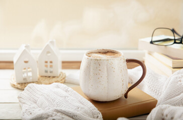 Winter.Winter composition, a cup of hot coffee, a decorative small snow-covered house and a warm sweater on a wooden table.Seasonal morning hot coffee.Merry Christmas and Happy New Year!Cozy interior