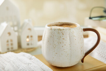 Winter.Winter composition, a cup of hot coffee, a decorative small snow-covered house and a warm sweater on a wooden table.Seasonal morning hot coffee.Merry Christmas and Happy New Year!Cozy interior