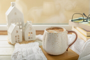 Winter.Winter composition, a cup of hot coffee, a decorative small snow-covered house and a warm sweater on a wooden table.Seasonal morning hot coffee.Merry Christmas and Happy New Year!Cozy interior