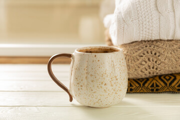 Autumn. Autumn composition, a hot cup of coffee and a warm sweater on a wooden textured table. Seasonal, morning hot coffee.Relaxing and still life concept. Cozy interior