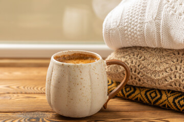 Autumn. Autumn composition, a hot cup of coffee and a warm sweater on a wooden textured table. Seasonal, morning hot coffee.Relaxing and still life concept. Cozy interior