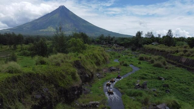 Aerial view of people driving through a river to Mayon Volcano