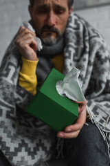 selective focus of pack with paper napkins in hand of diseased man on blurred background.