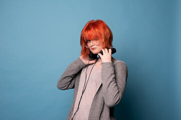 Stylish teenage girl with headphones on blue background.