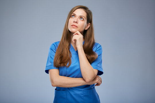 Serious thinking nurse woman in blue medical uniform looking up. Isolated female portrait.