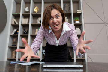 Angry female office worker standing on the table and demonstrating her irritation and...