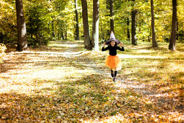Cute teenage girl in a witch costume runs through the autumn forest