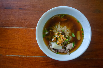 Asian delicatessen, beef noodles with soup on wood table.
