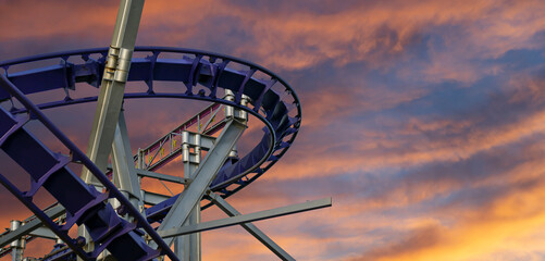 Attraction roller-coaster (switchback) against the background of a romantic evening sky