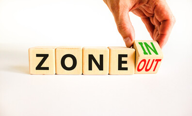 Zone in or out symbol. Concept words Zone in and Zone out on wooden cubes. Beautiful white table white background. Businessman hand. Business zone in or out concept. Copy space.