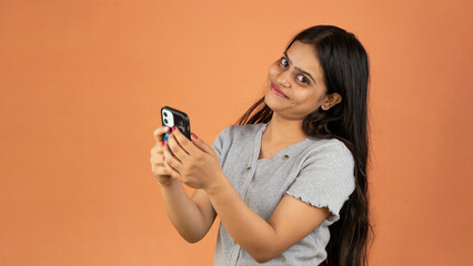 Cheerful young woman holding smartphone isolated over color background