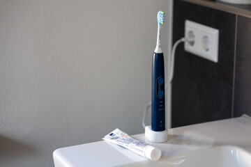 elektrische Zahnbürste auf dem Waschbecken mit Zahnpasta und Steckdose