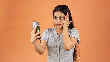 Surprised young woman using mobile phone, shocked face Indian woman holding smartphone, Looking at cell phone screen, isolated over color background