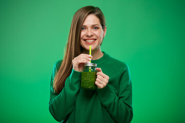 Smiling woman drinking green smoothie. Isolated female advertising portrait on green.