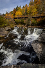Fototapeta na wymiar Tanners Falls in the Poconos near Honesdale, PA, on a brilliant fall day, which features multiple cascades and a historic bridge 