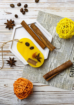 Aroma sashet with coffee beans, cinnamon and star anise on a white tray. Cinnamon straws and coffee beans in the background. Light wooden background, top view
