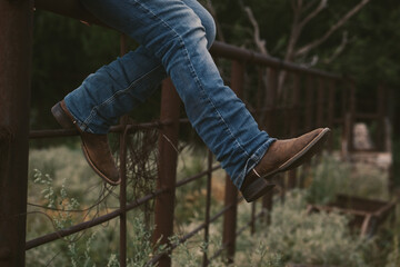 Western lifestyle concept with person sitting on fence in cowboy boots. - 537846550