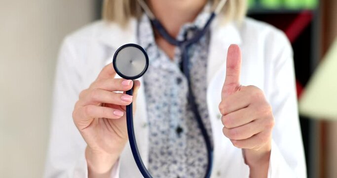 Closeup of female doctor hands holding stethoscope showing thumb up