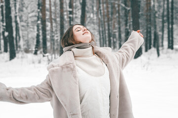 Obraz premium Young beautiful girl in snowy cold winter frost forest. Walking, having fun, laughing in stylish clothes, fur coat, woolen shawl, bonnet. Snow trees lovestory. Romantic date, weekend