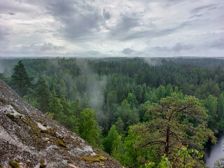 View from Katajavuori Hill - fog raising over the lake, rocks and forest in the Repovesi National Park after the rain on cloudy summer day