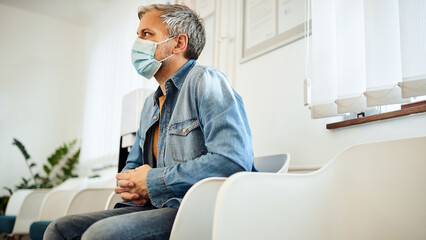 Man with protective face mask sitting in waiting room at medical clinic.