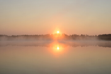Obraz premium Sunrise on a forest lake. Beautiful foggy morning nature landscape. Calm scene. Dawn, mist, calm water