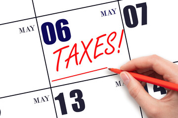 Hand drawing red line and writing the text Taxes on calendar date May 6. Remind date of tax payment