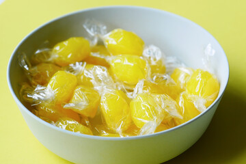 lemon candy in a bowl on yellow background 