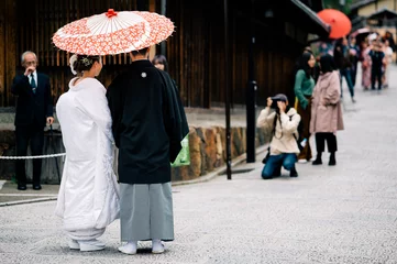 Selbstklebende Fototapeten A japanese couple on their wedding day dressed up in traditional kimono taking photo shots in kyoto © vacancylizm