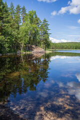 Fototapeta na wymiar View to Hermusenlahti lake from Talas Campfire Site in Repovesi National park on beautiful summer day. White clouds reflecting in blue calm water