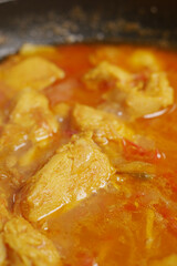 cooking chicken curry in a cooking pan 