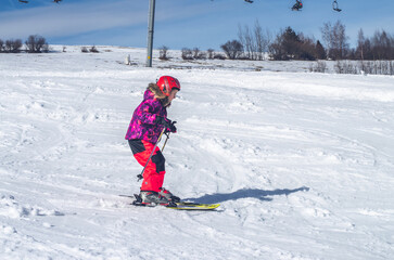 Fototapeta na wymiar little girl skiing downhill in snowy resort