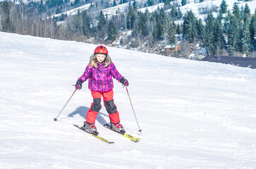 little girl skiing downhill in snowy resort