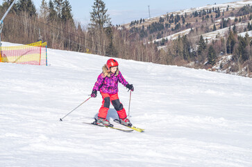 little girl skiing downhill in snowy resort
