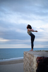 Woman performing yoga positions in a natural setting by the sea.