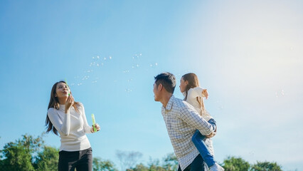 Happy asian family in the garden They are having fun playing and blowing bubbles. and enjoyed ourselves together in the green garden. Family enjoying sunny fall day in nature.
