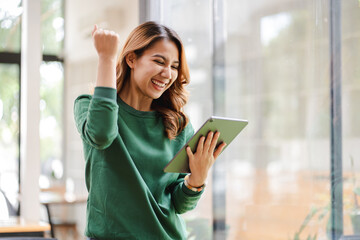 Asian girls are excited about victory. hand holding a digital tablet at her office