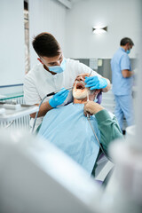 Obraz premium Young dentist examining teeth of senior patient at dental clinic.
