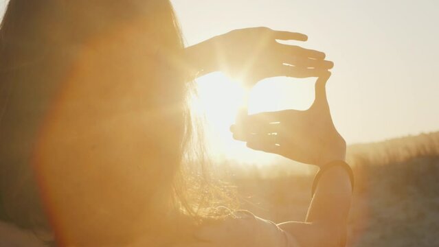 Female photographer prepares for shooting and creates frame with her hands