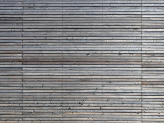 Thin wooden planks horizontal on a building exterior. Architectural feature on a facade. Grey pattern perfect as a background. Empty texture of the woodgrain structure. Natural construction material.
