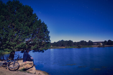 Obraz premium lonely man in a lake at night, sky with stars, and bike next to the young man, lagoon in monte escobedo zacatecas 