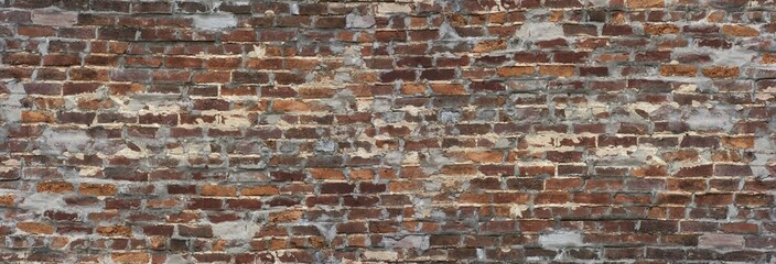 Long old brick wall background with red and orange bricks and holes filled in with concert.