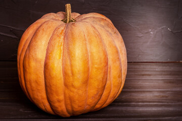 Orange pumpkin on a black wooden background. Harvest, Halloween.