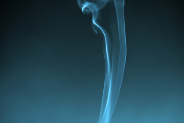 Obraz premium Illuminated blue green smoke of incense stick against black background. Photo taken October 13th, 2022, Zurich, Switzerland.