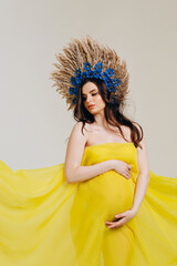 Cute pregnant woman wrapped in a yellow cloth and with a wreath on her head.The concept of love for...