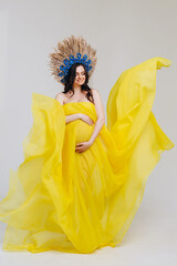 Cute pregnant woman wrapped in a yellow cloth and with a wreath on her head.The concept of love for...